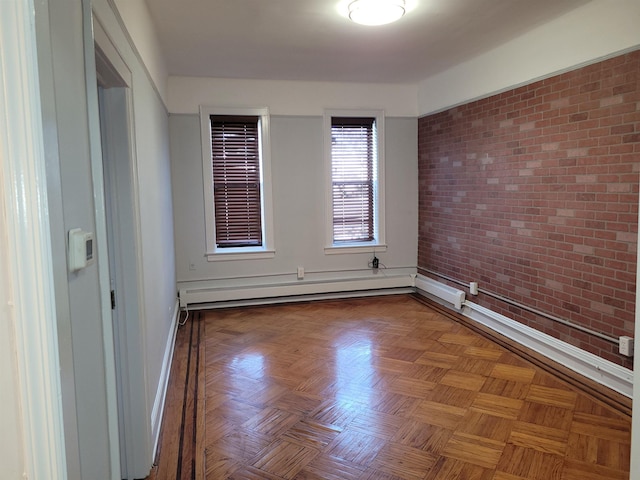 spare room featuring a baseboard heating unit, baseboards, and brick wall