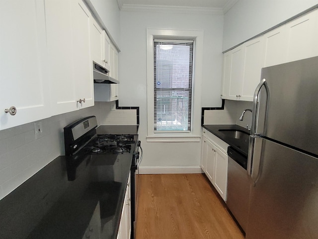 kitchen featuring wood finished floors, ornamental molding, a sink, under cabinet range hood, and appliances with stainless steel finishes