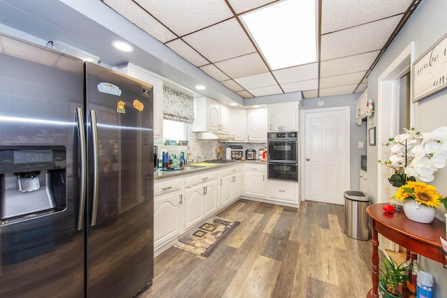 kitchen featuring dark wood finished floors, stainless steel appliances, white cabinets, light countertops, and decorative backsplash