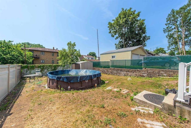 view of yard with a fenced in pool, an outdoor structure, a storage shed, and a fenced backyard