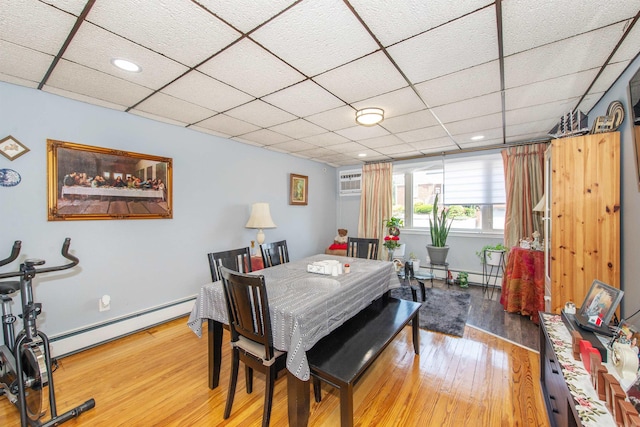 dining area with a baseboard radiator, a paneled ceiling, and wood finished floors