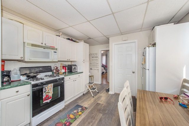 kitchen featuring a drop ceiling, white cabinets, white appliances, and dark wood-type flooring