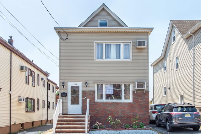 view of front of home featuring brick siding, entry steps, and a wall mounted AC