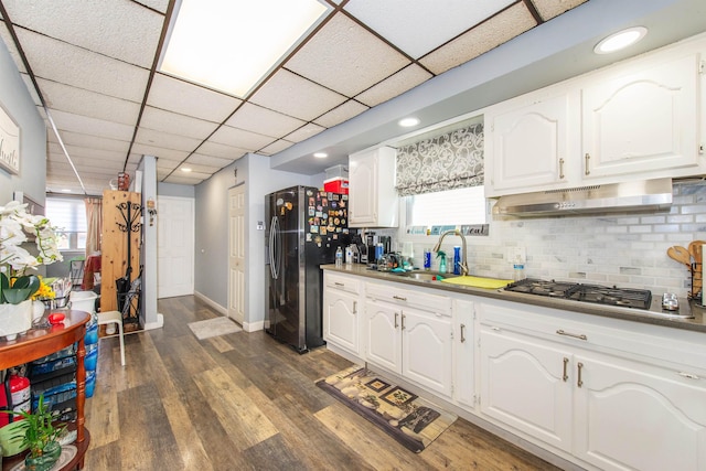 kitchen featuring a sink, under cabinet range hood, fridge with ice dispenser, white cabinetry, and dark wood-style flooring