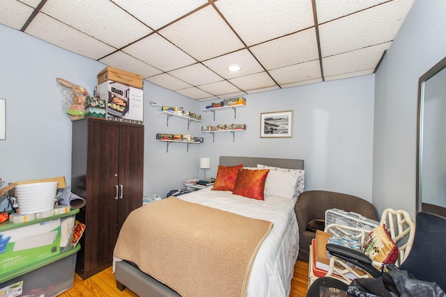 bedroom with light wood finished floors and a paneled ceiling