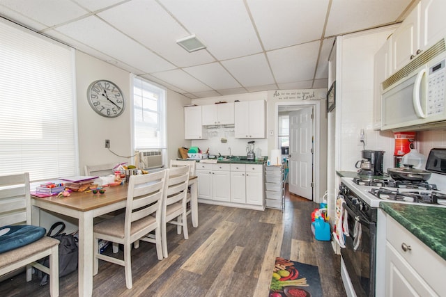 kitchen featuring white cabinetry, dark wood-type flooring, gas range oven, and white microwave