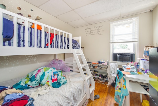 bedroom with cooling unit, a paneled ceiling, and wood finished floors