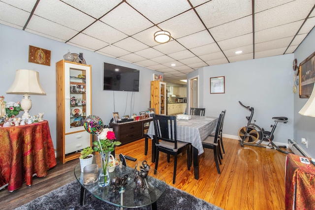 dining area featuring recessed lighting, wood finished floors, baseboards, and a drop ceiling