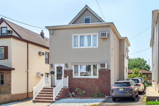 view of front of home with brick siding and an AC wall unit