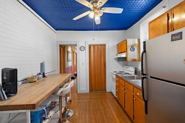 kitchen with dark wood-type flooring, decorative backsplash, white electric stove, stainless steel refrigerator, and ceiling fan