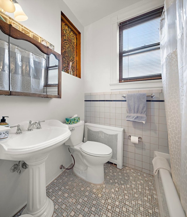 bathroom featuring tile walls, tile patterned flooring, radiator heating unit, and a wealth of natural light