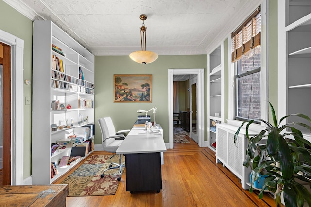 office area with built in shelves, light wood-type flooring, and radiator