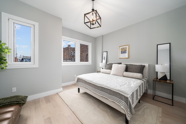 bedroom with light hardwood / wood-style floors and an inviting chandelier