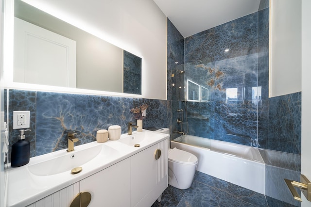 full bathroom with tile walls, vanity, tiled shower / bath combo, and toilet