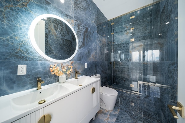 bathroom with tile walls, a shower with door, vanity, and toilet