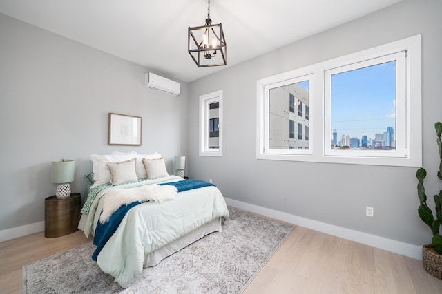 bedroom with an AC wall unit, multiple windows, hardwood / wood-style flooring, and a notable chandelier