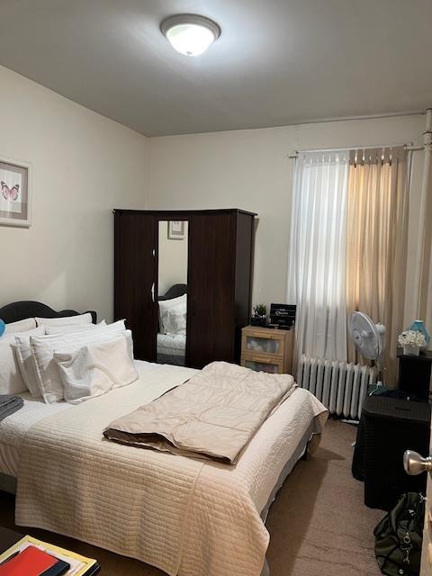 carpeted bedroom featuring radiator and vaulted ceiling