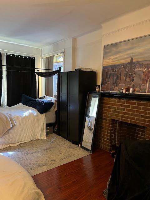 bedroom with a brick fireplace and wood finished floors