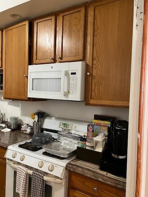 kitchen with dark countertops, brown cabinets, and white appliances