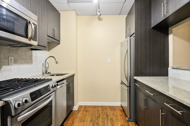 341 Monmouth St Unit 104D, Jersey City, NJ 07302 - kitchen featuring stainless steel appliances, tasteful backsplash, wood finished floors, light stone counters, and dark brown cabinets