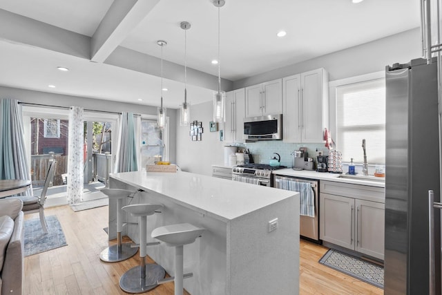 kitchen with a breakfast bar area, stainless steel appliances, decorative backsplash, pendant lighting, and sink