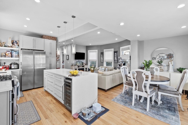 kitchen featuring a center island, white cabinetry, stainless steel appliances, wine cooler, and hanging light fixtures