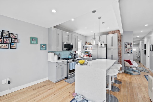 kitchen with pendant lighting, appliances with stainless steel finishes, a center island, tasteful backsplash, and a breakfast bar area