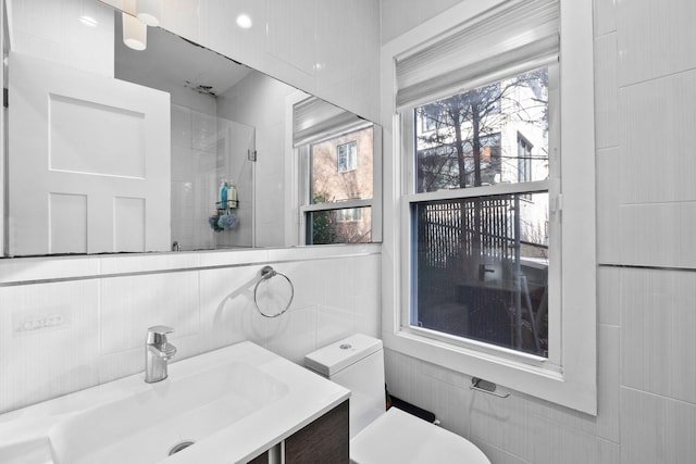 bathroom with tile walls, toilet, and vanity