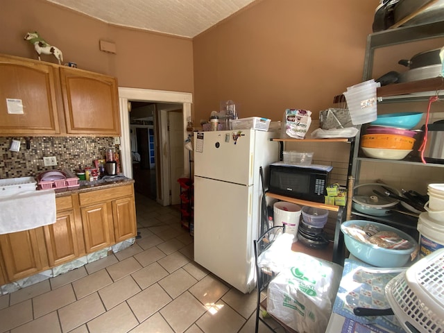 143 64th St, West New York, NJ 07093 - kitchen with freestanding refrigerator, black microwave, light tile patterned floors, and backsplash