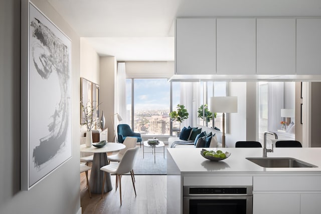99 Hudson St Unit 4903, Jersey City, NJ 07302 - kitchen with a sink, oven, wood finished floors, modern cabinets, and white cabinetry