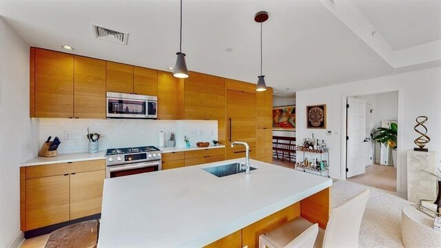10 Provost St Unit 1004, Jersey City, NJ 07302 - kitchen featuring stainless steel appliances, a sink, decorative backsplash, light countertops, and hanging light fixtures