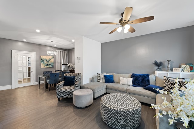 living room with ceiling fan with notable chandelier and dark hardwood / wood-style floors