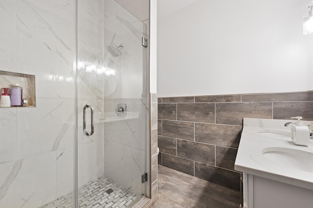 bathroom with tile walls, vanity, and a shower with door