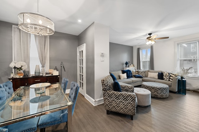 living room featuring dark wood-type flooring and ceiling fan with notable chandelier