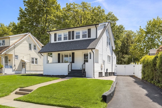 bungalow featuring a gate, roof with shingles, a porch, a front lawn, and driveway