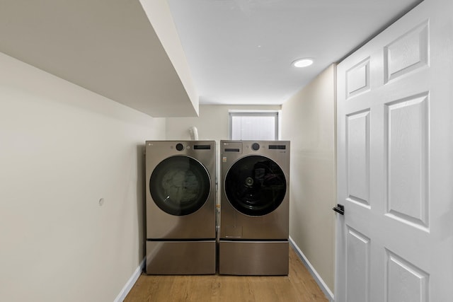 washroom with washer and dryer, baseboards, and light wood finished floors