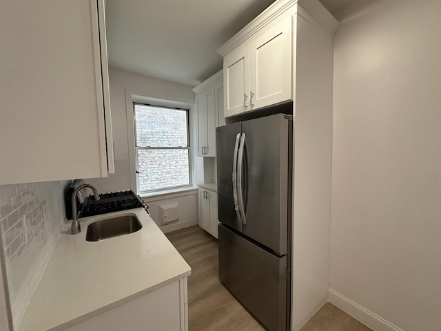 311 79th St Unit 37, North Bergen, NJ 07047 - kitchen featuring freestanding refrigerator, white cabinetry, light countertops, light wood-type flooring, and decorative backsplash