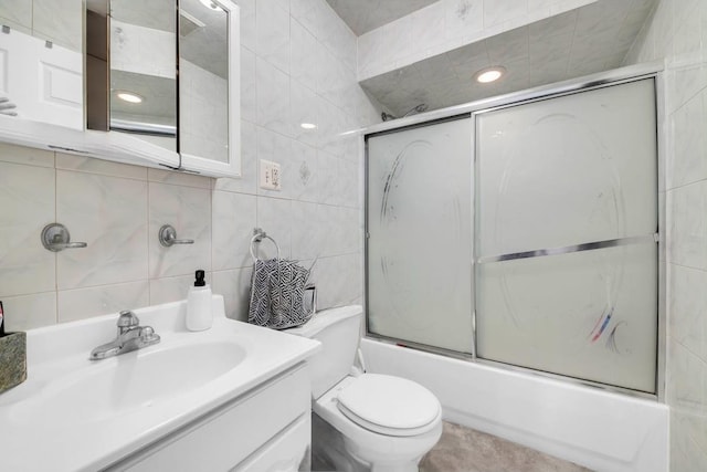 full bath featuring tile walls, vanity, toilet, and bath / shower combo with glass door