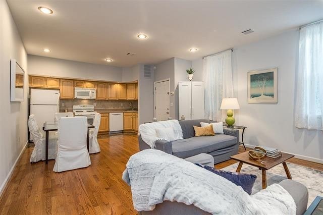 living area featuring recessed lighting, visible vents, baseboards, and wood finished floors