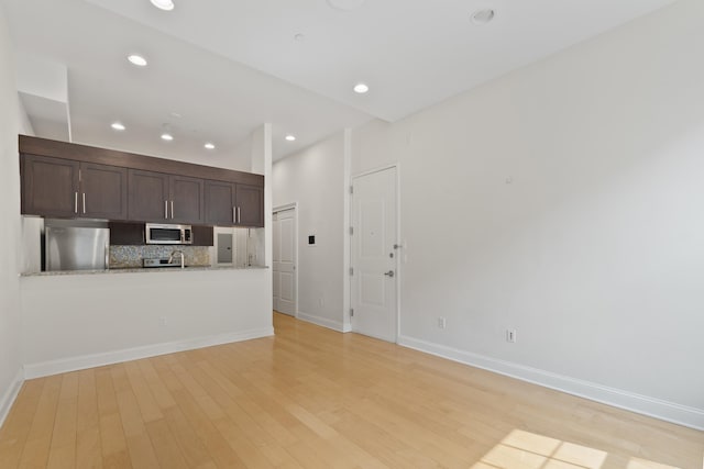 104 Tidewater St Unit 1A, Jersey City, NJ 07302 - kitchen featuring stainless steel appliances, light wood-style flooring, dark brown cabinets, tasteful backsplash, and recessed lighting