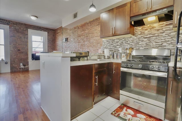 37 Harmon St, Jersey City, NJ 07304 - kitchen featuring a peninsula, light countertops, under cabinet range hood, visible vents, and stainless steel range with gas cooktop