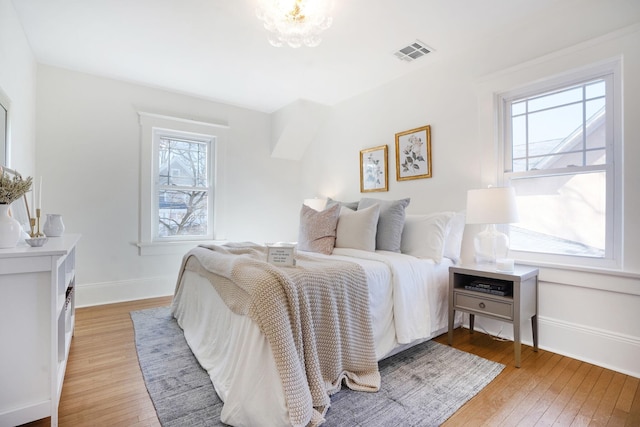 bedroom with light wood-type flooring, visible vents, and baseboards