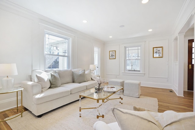 living area with crown molding, wood finished floors, and a decorative wall