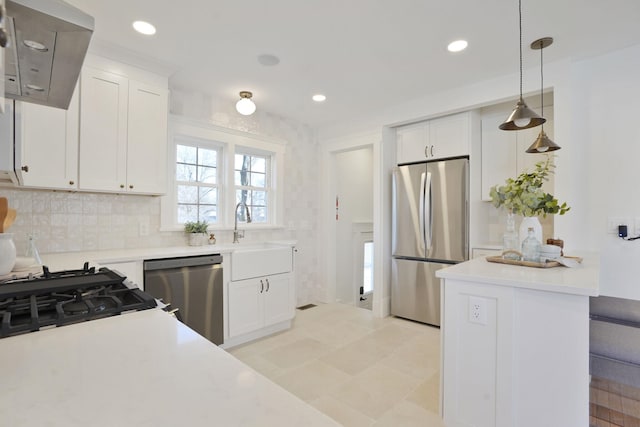 kitchen with light countertops, hanging light fixtures, appliances with stainless steel finishes, white cabinetry, and a sink