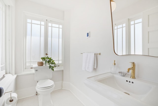 bathroom featuring baseboards, a sink, toilet, and tile patterned floors