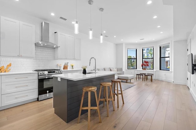 2602 Palisade Ave, Weehawken, NJ 07086 - kitchen featuring gas stove, wall chimney range hood, a sink, light countertops, and tasteful backsplash