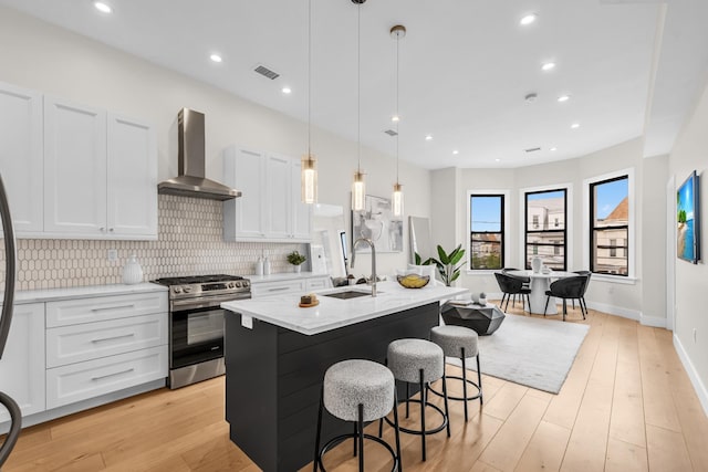 2602 Palisade Ave, Weehawken, NJ 07086 - kitchen with gas range, wall chimney exhaust hood, a sink, an island with sink, and light stone countertops
