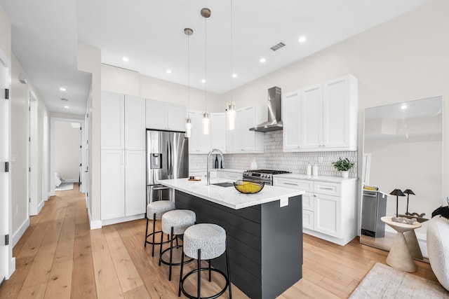 2602 Palisade Ave, Weehawken, NJ 07086 - kitchen with wall chimney exhaust hood, a sink, stainless steel appliances, light wood-type flooring, and a kitchen bar