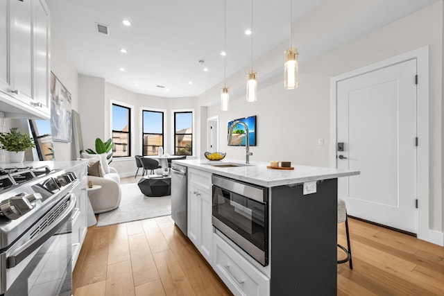 2602 Palisade Ave, Weehawken, NJ 07086 - kitchen with appliances with stainless steel finishes, light wood-type flooring, a sink, light stone counters, and a kitchen bar