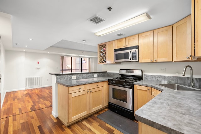 700 1st St Unit 6D, Hoboken, NJ 07030 - kitchen featuring appliances with stainless steel finishes, a peninsula, light brown cabinets, wood finished floors, and dark countertops